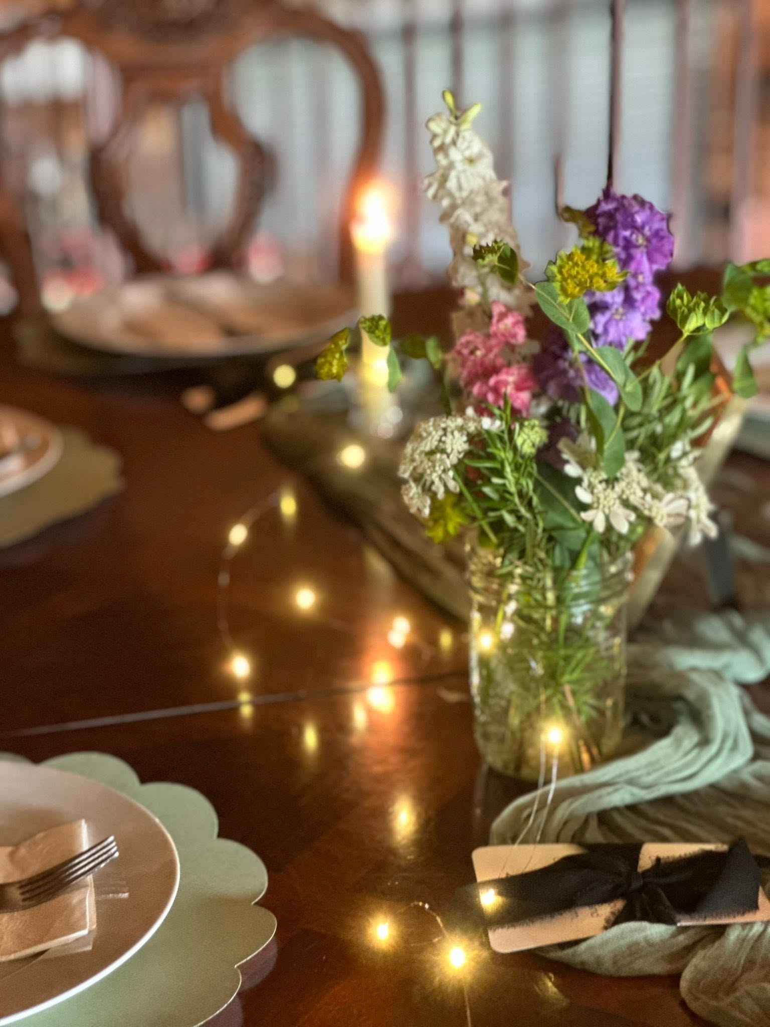 Flowers and candles arranged on a wooden table with wine glasses